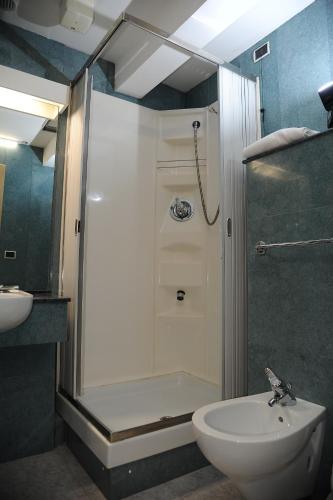a bathroom with a shower and a toilet and a sink at Hotel Sole Family Hotel in Predazzo