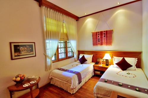 a hotel room with two beds and a window at The Hotel by the Red Canal in Mandalay