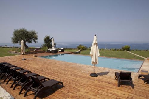 a swimming pool with chairs and an umbrella at Villa Mediterraneo in Fuscaldo