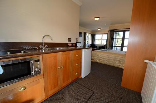 a kitchen with a sink and a bed in a room at Lantern Court Motel in Reefton