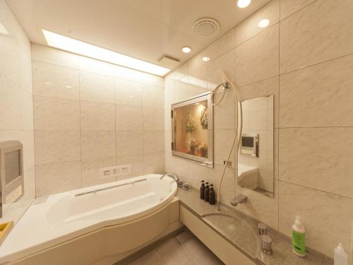 a white bathroom with a tub and a shower at Hotel Fine Sakai in Sakai