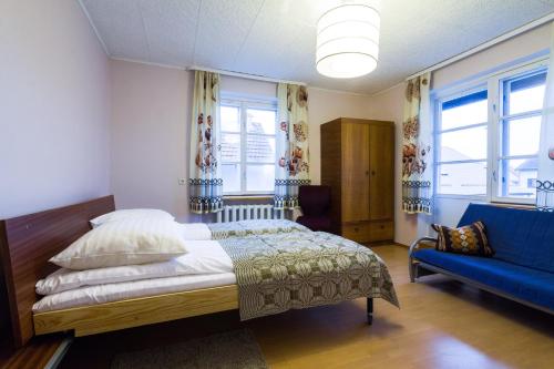 1 dormitorio con 1 cama y 1 sofá azul en Avirės Namai, en Druskininkai