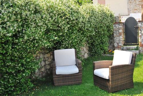 two chairs sitting in the grass next to a hedge at Monte Grappa Guest House in Romano D'Ezzelino