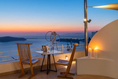 Un balcón con sillas y una mesa con vistas al océano. en La Maltese Caldera Concept, en Imerovigli