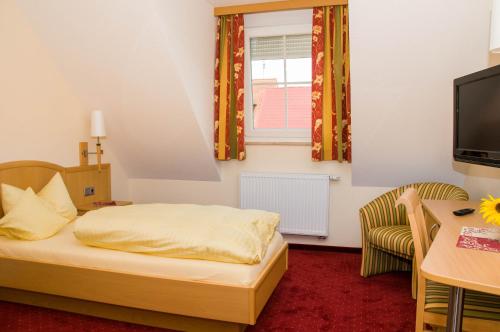 Dormitorio con cama, escritorio y TV en Gasthof Rose, en Flachslanden