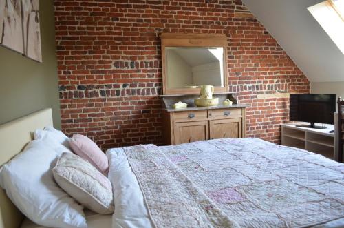 a bedroom with a brick wall and a bed and a mirror at B&B Hof Ter Haegen in Vollezele