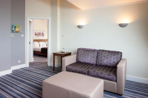 a living room with a couch and a stool at Holiday Inn Glasgow - East Kilbride by IHG in East Kilbride