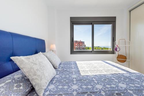 sypialnia z niebieskim łóżkiem i oknem w obiekcie Apartamento Playa Marinsa w mieście Torre del Mar