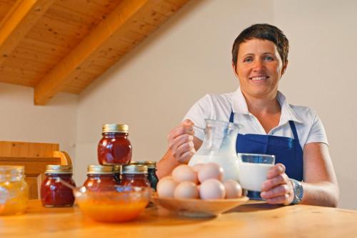 a woman in an apron sitting at a table with eggs at Fassnauerhof Ridnaun in Racines