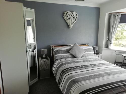 a bedroom with a bed with a heart on the wall at Rockville Amlwch LL68 0TE, UK Apartment in Llanfflewyn