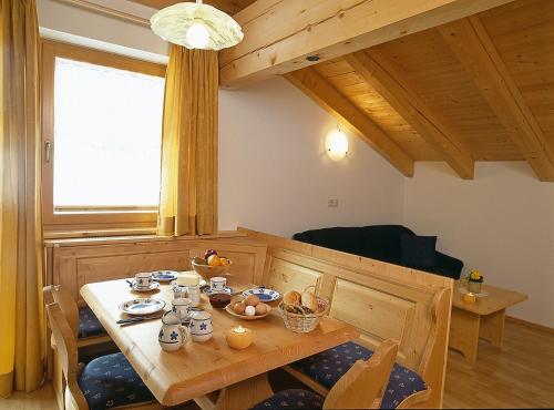 uma sala de jantar com uma mesa de madeira e cadeiras em Fassnauerhof Ridnaun em Racines
