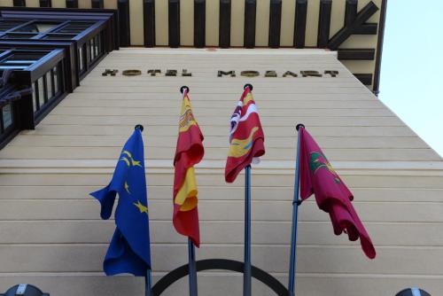 three flags on poles in front of a building at Hotel Mozart in Valladolid