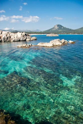 a large body of water with rocks and blue water at Bell Port Hotel in Cala Ratjada
