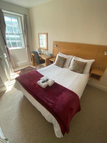 a bedroom with a large bed with two towels on it at The Old Court Hotel in Witney