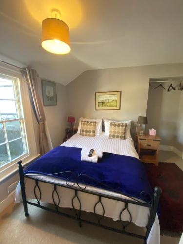 a bedroom with a large bed with a blue blanket at The Old Court Hotel in Witney