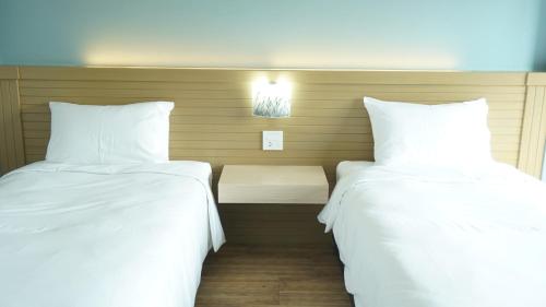 two beds in a hotel room with white sheets at MtriO Hotel Korat in Nakhon Ratchasima