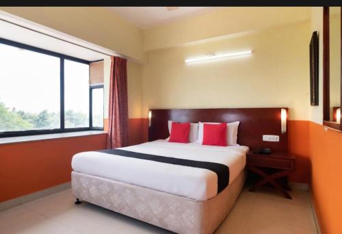 1 dormitorio con 1 cama grande con almohadas rojas en Hotel Vassi Palaze, en Chengalpattu