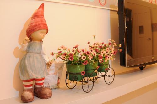 a doll next to a pot of flowers on a shelf at Lotus Hostel Beicheng Zhuang in Luodong