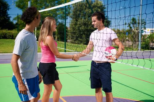 a group of three people shaking hands on a tennis court at San Francesco Camping Village in Desenzano del Garda