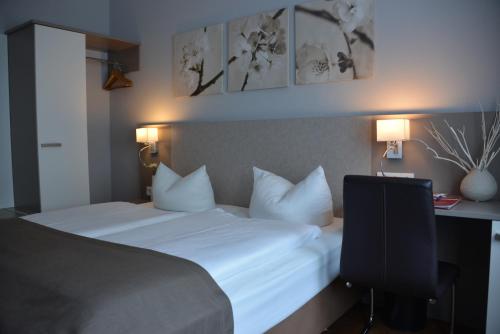 a bedroom with a bed with white pillows and a desk at Arthotel Munich in Munich