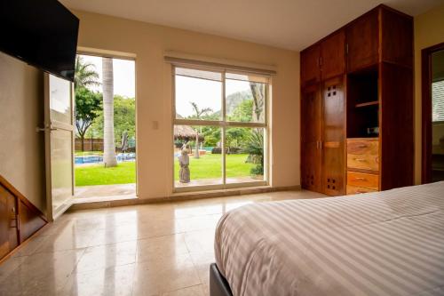 a bedroom with a bed and a large window at Alilo by Muuk in Tepoztlán