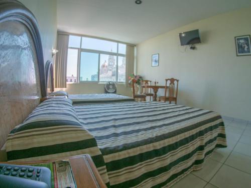 a bedroom with a large bed with a striped blanket at Hotel Plaza Sahuayo in Sahuayo de José María Morelos