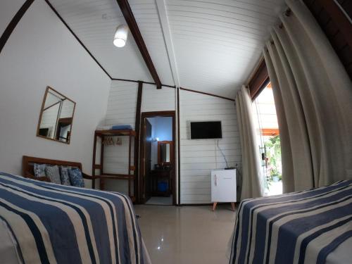 a bedroom with two beds and a tv in a room at Pousada Bela Vista in Abraão