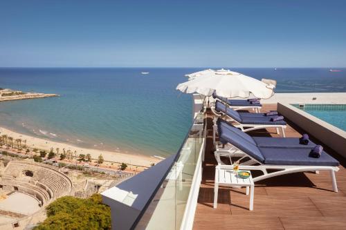 a row of chairs and umbrellas on a balcony overlooking the ocean at H10 Imperial Tarraco 4 Sup in Tarragona