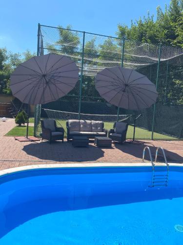 two umbrellas and two chairs and a swimming pool with chairs and chairsuggest at Smiley Rooms in Avrig
