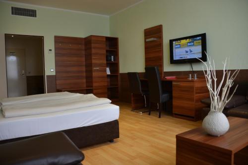 a room with a bed and a desk and a television at Arthotel Munich in Munich