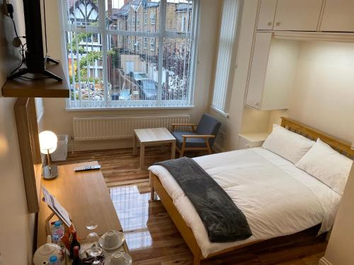 1 dormitorio con cama, mesa y ventana en Chatsworth Guest House, en Londres