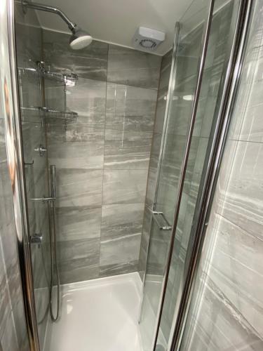 a shower with a glass door in a bathroom at Chatsworth Guest House in London