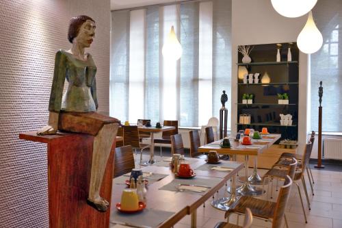 a statue of a woman sitting on a table in a restaurant at Arthotel Munich in Munich