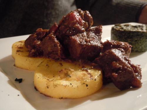 a plate of food with meat and potatoes on it at Locanda nel Cassero in Civitella Marittima