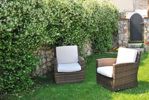 two chairs sitting in the grass next to a hedge at Monte Grappa Guest House in Romano D'Ezzelino