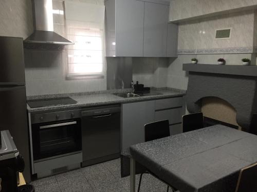 a kitchen with a table and a sink and a stove at Casa Porta de Santiago in Pinhel