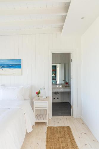 a white bedroom with a bed and a bathroom at Casa Flor in Punta del Este