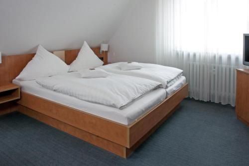 a bedroom with a bed with white sheets and a television at Hotel Restaurant Vogt in Rietberg