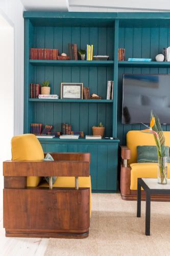 a living room with a blue wall and yellow chairs at Casa Flor in Punta del Este