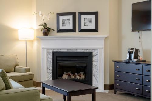 a living room with a fireplace and a table at Amsterdam Inn & Suites Sussex in Sussex