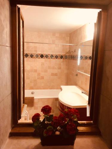 La salle de bains est pourvue d'une baignoire, d'un lavabo et de fleurs. dans l'établissement Lodges du Canal St-Dominique, à Annecy