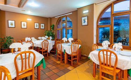 uma sala de jantar com mesas, cadeiras e janelas em Tierra de la Reina em Boca de Huérgano