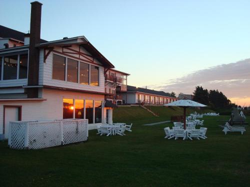 a building with tables and umbrellas on a lawn at Hotel Motel Belle Plage in Matane