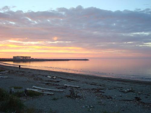 a beach at sunset with a pier in the water at Hotel Motel Belle Plage in Matane