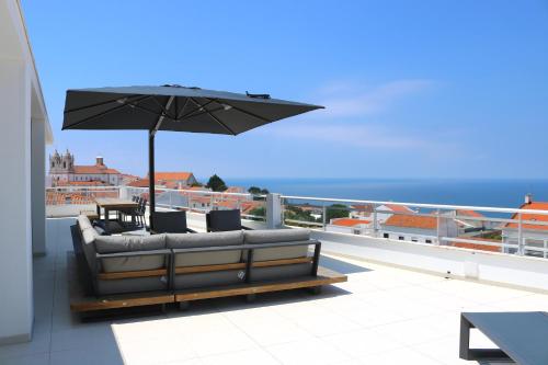a patio with a couch and an umbrella at Pico Do Feliz - The Penthouse & The Village By Silver Prop in Nazaré