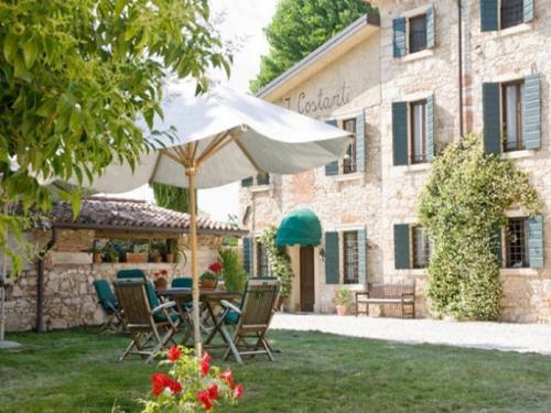 a table and chairs with an umbrella in front of a building at I Costanti in Caldiero