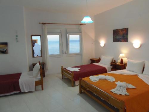 Habitación de hotel con 2 camas y ventana en Studios Milos Skopelos-Where the Sea Meets the Sky, en Skopelos Town