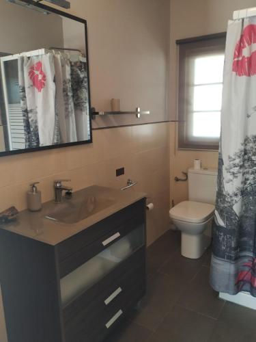 a bathroom with a sink and a toilet and a mirror at La casa del estanque in Olocau del Rey