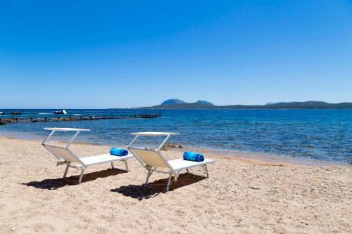 two chairs sitting on a beach next to the water at Villa Smeralda Punta Lada Porto Rotondo in Porto Rotondo