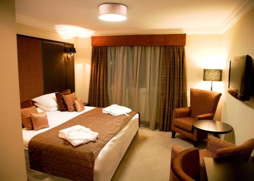 a hotel room with a bed and a chair at The Popinjay Hotel in Larkhall